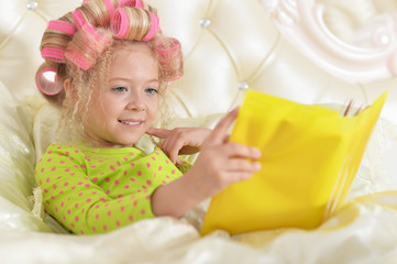 Obraz na płótnie Canvas little girl in hair curlers with book