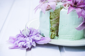 Creamy cake with clematis flowers on the wooden table. Shallow depth of field.