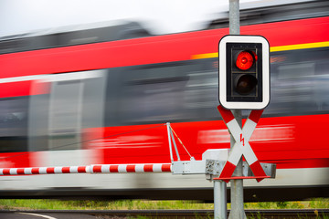 An einem Bahnübergang zeigt die Ampel rot und ein Zug fährt vorbei