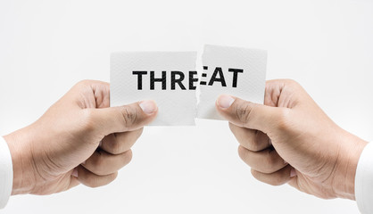 Hand tearing paper with threat word.Belief motivation overcoming