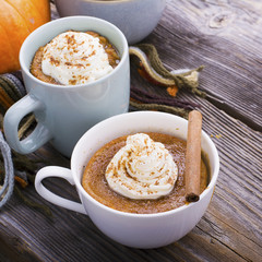 Quick meal breakfast snack in the microwave. Fragrant homemade pumpkin pie fall for five minutes in the cup portions with whipped cream and cinnamon on a wooden background