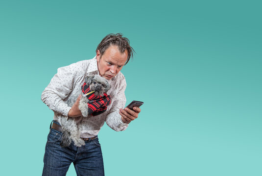 Mann mit kleinem kranken H&uuml;ndchen sucht auf Smartphone nach Hilfe.