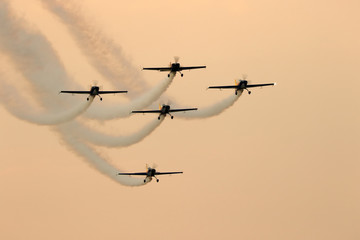 Silhouette of airplanes performing acrobatic flight at sundown.