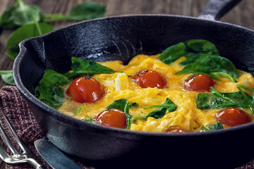 Spinach frittata with cherry tomato in iron skillet