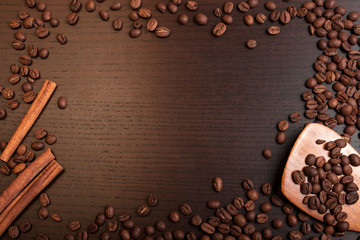 Coffee beans and cinnamon on brown table with space for text