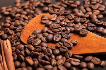 Coffee beans in wooden scoop on brown table