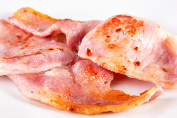 Fried bacon slices on a white plate. SDOF