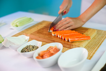 Close up picture of young lady's hands slicing crab sticks