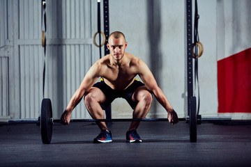 Fototapeta na wymiar Young athletic man doing weightlifting workout with barbell at t