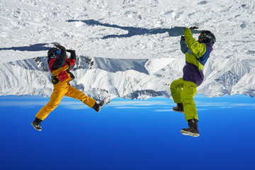 Two snowboarders are on hand upside down in high mountains