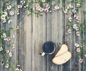 Coffee mug with bread on weathered wooden background with field