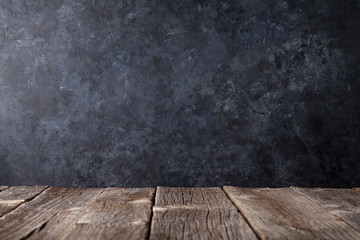 Old wooden table in front of black wall