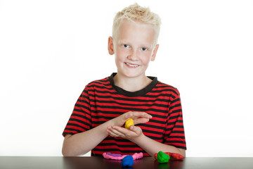 Happy young boy playing with modeling clay