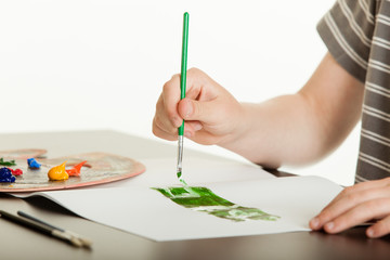 Young boy painting green lettering on a sketchpad