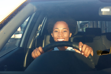 Young african woman driving a car and smiling
