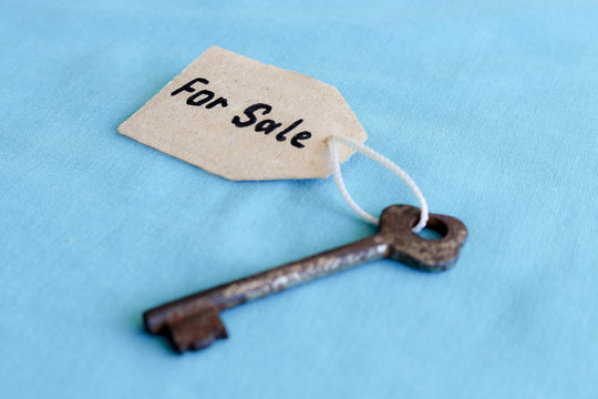 The concept of sale of real estate - the old key with the inscription on the tag , on the turquoise background.
