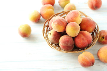 Sweet peach fruit in basket on white wooden table