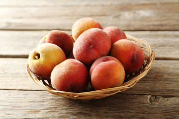 Sweet peach fruit in basket on grey wooden table