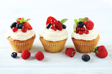 Tasty cupcakes with berries on white wooden table
