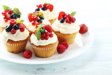 Tasty cupcakes with berries on white wooden table