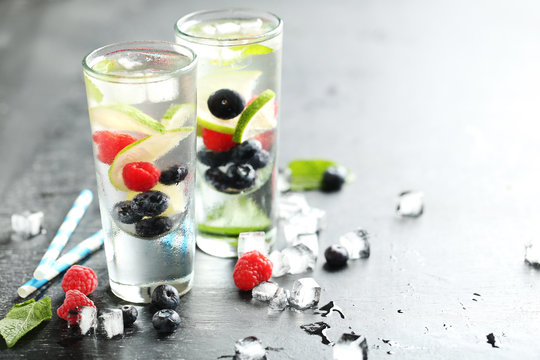 Detox water in glasses with berries on wooden table