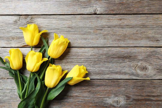 Bouquet of yellow tulips on a grey wooden table