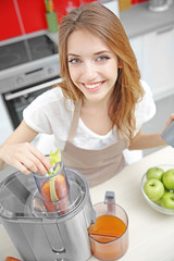 Beautiful girl making juice in kitchen