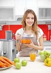 Beautiful girl making juice in kitchen