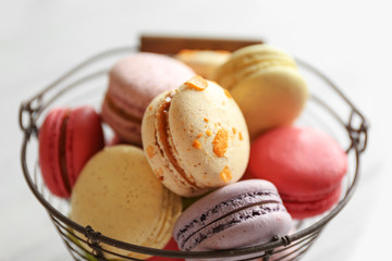 Colorful tasty macaroons in metallic bowl on light background