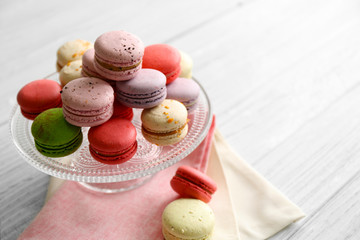 Colorful tasty macaroons in glass stand on light background