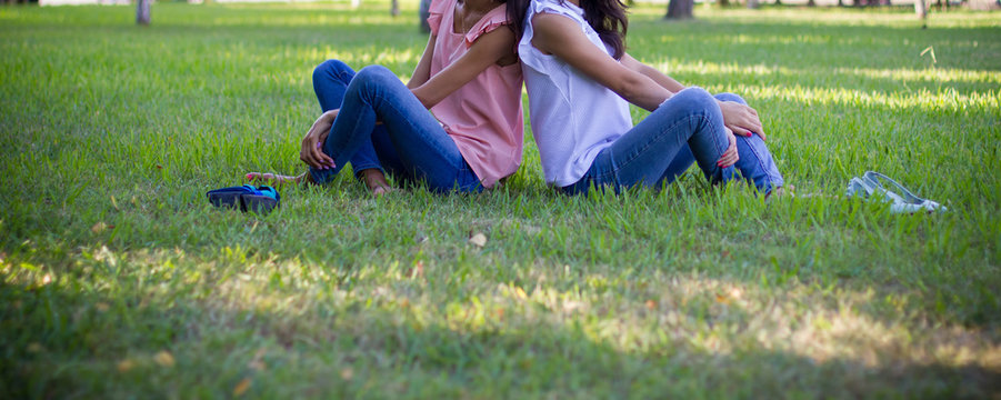  Two teen girl friends siting on grass