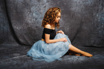 beautiful and delicate ballerina in a studio on gray background