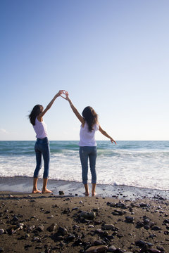 Two teen girl friends walk on the beach