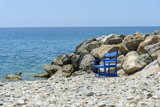 Lonely bench at stone beach of Paleochora town on Crete island, Grecee