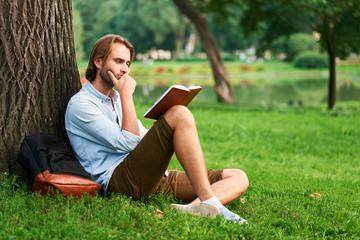 Serious student in park of campus read a book