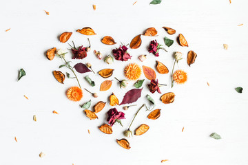heart symbol made of dried flowers and autumn leaves, top view,