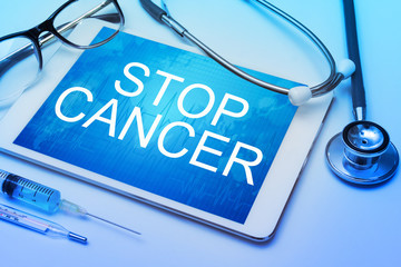Stop Cancer word on tablet screen with medical equipment on background