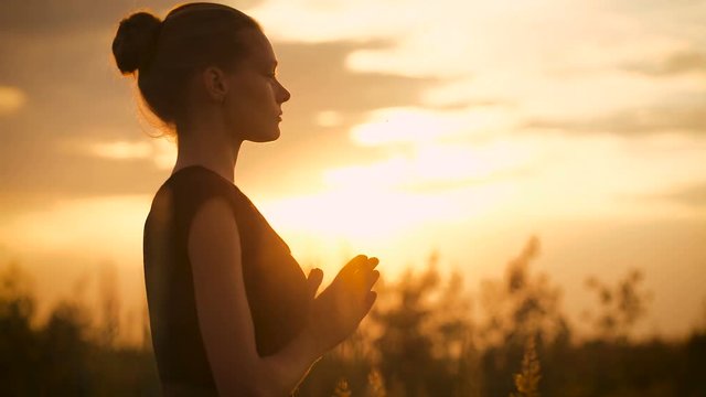 Beautiful young healthy woman doing yoga exercise during sunset