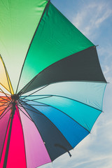 open colorful rainbow umbrella on blue sky background, vintage look