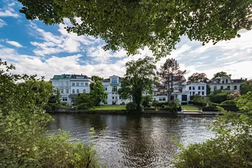 Architectural buildings along the Alster canal in Hamburg Germany   Luxury old mansions Winterhude neighbourhood against blue sky on sunny summer day, image for real estate agent business realtor blog © HBpictures