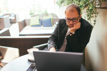 young aspiring businessman working at a laptop in a cafe