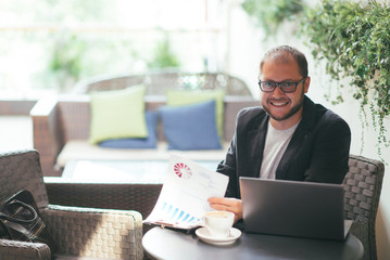Obraz premium young aspiring businessman working at a laptop in a cafe