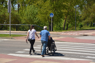 empujando una silla de ruedas por un paso de cebra