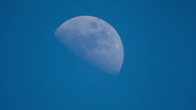 a half moon moving across a blue sky