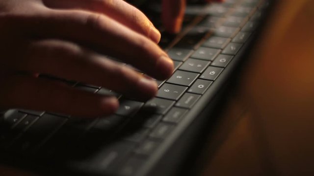 Tablet Keyboard Typing. The camera trucks along a close up of fingers typing on a black tablet computer keyboard.