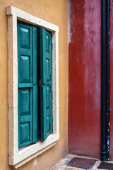 Green wooden window on yellow and red walls