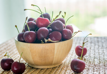 Selective focus of Cherries with water drops in wooden bowl