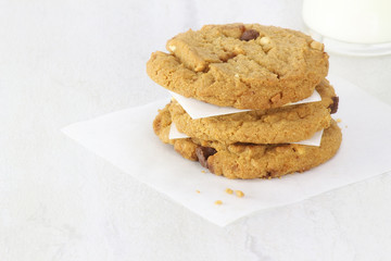 Stack of chocolate chip cookies with milk in background.