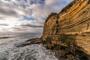Fototapeta na wymiar Rocky cliff with cloudy sky and ocean at Sunset Cliffs in San Diego, California.