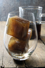 Coffee ice cubes in a glass with coffee in the background ready to make ice coffee